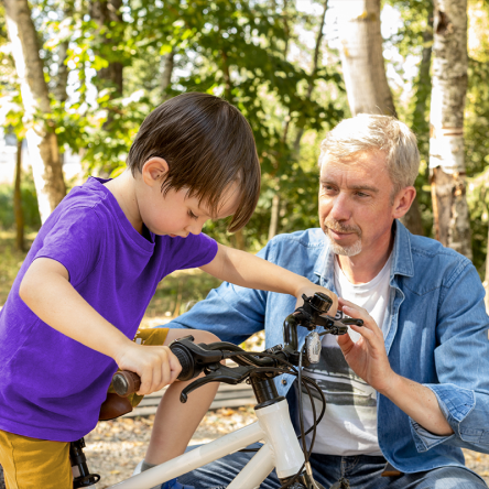 A father teaching his son how to ride a bike.