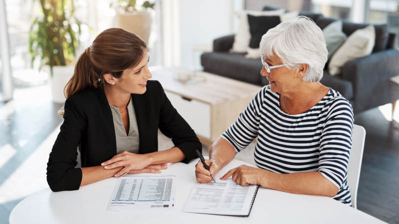 A financial professional meeting with senior-aged female client to review an estate plan.