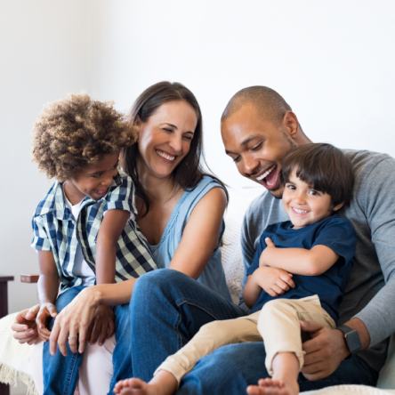 Mother and father snuggling with two children while laughing.