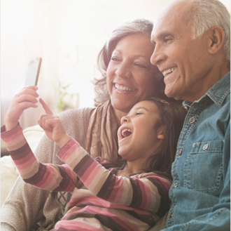 An older couple and grandchild laughing at content on a mobile phone