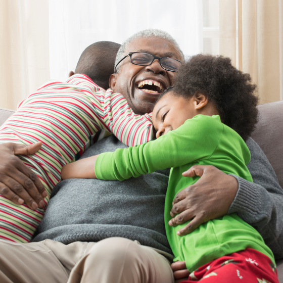 A grandfather happily hugging his grandchildren, knowing his family his protected with whole life insurance.