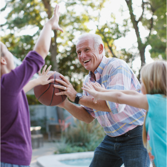 A grandfather plays basketball with his two grandchildren.