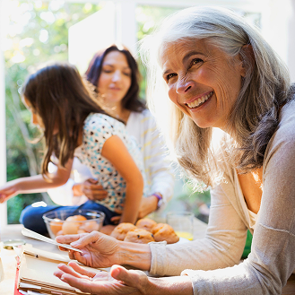 Grandmother, who represents a potential Protective Secure Saver fixed annuity client, reviews recipe while cooking with daughter and granddaughter.