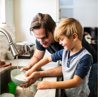 A father washing dishes with his son.