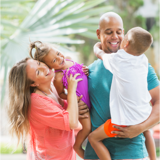 A mother and father playfully embrace their two children, feeling secure because they have life insurance